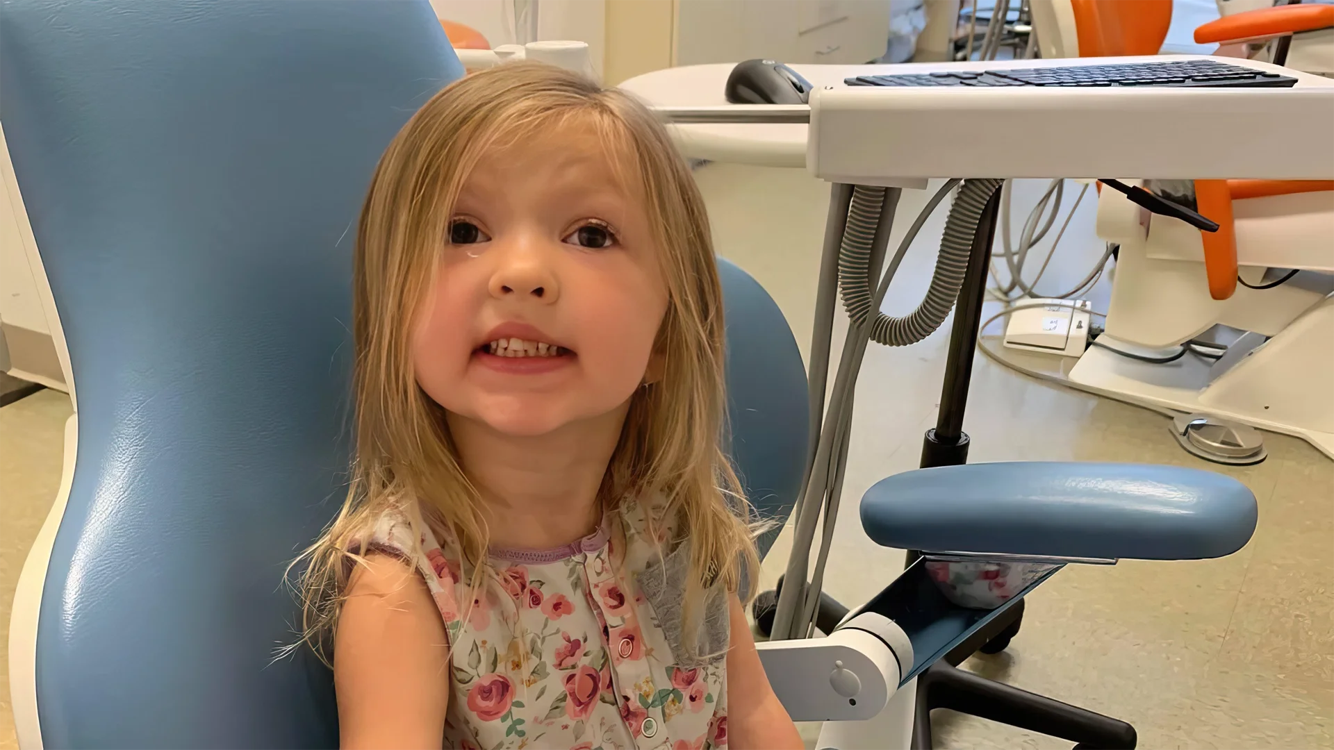 girl smiles at camera while sitting in dental chair